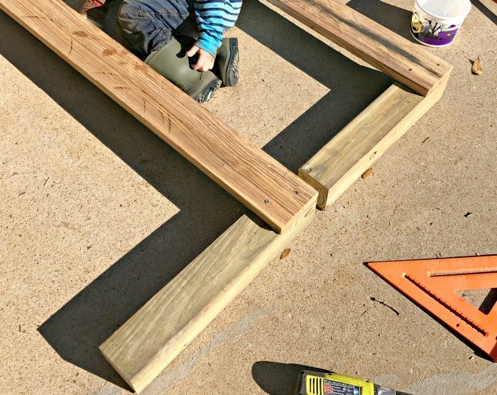 Build this fun and easy pea gravel play area, backyard activity wall, and DIY Rustic Bench. All the fun of a sand box, without the mess. 