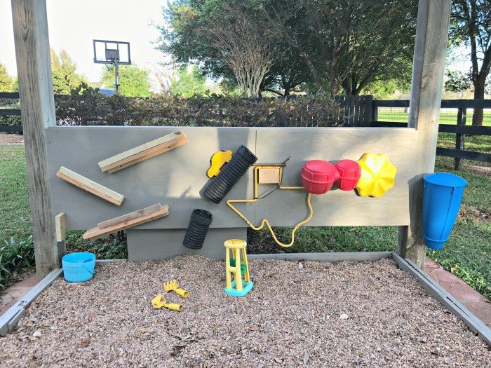 Build this fun and easy pea gravel play area, backyard activity wall, and DIY Rustic Bench. All the fun of a sand box, without the mess. 