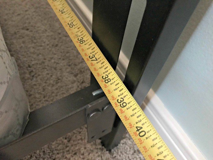 Measuring how wide the metal bed frames are with measuring tape.