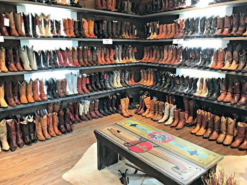 Room lined with shelves of cowboy boots. The Spring and Fall Round Top Texas Antiques and Flea Markets are great! BUT you can find Fun, Art & Furniture Shopping in Round Top, Texas year round, guys! Check out photos from the shops in town. #RoundTop #TexasTravel #AbbottsAtHome
