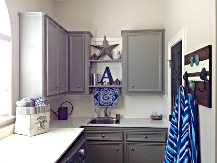 Dark grey cabinets with a white quartz counter in a Laundry Room with blue accents. This DIY Laundry Room Makeover Ideas post is full of Before & After Makeover Photos, budget-friendly DIY ideas, and Laundry Room decor. #LaundryRoom #BeforeandAfter #AbbottsAtHome