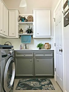 Creamy white cabinets and walls with grey lower cabinets, with plants, wood accents, and teal pops of color. This post is full of Before & After Makeover Photos, budget-friendly DIY ideas, and Laundry Room decor. #LaundryRoom #BeforeandAfter #AbbottsAtHome