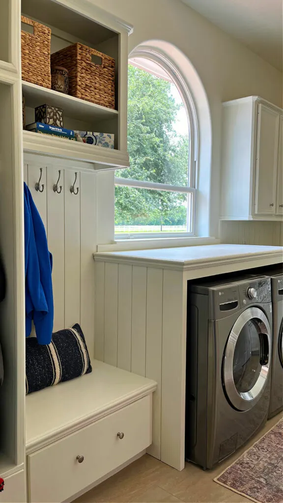 Image of a white laundry room mudroom combo with shiplap and a DIY laundry table over  the washer and dryer.