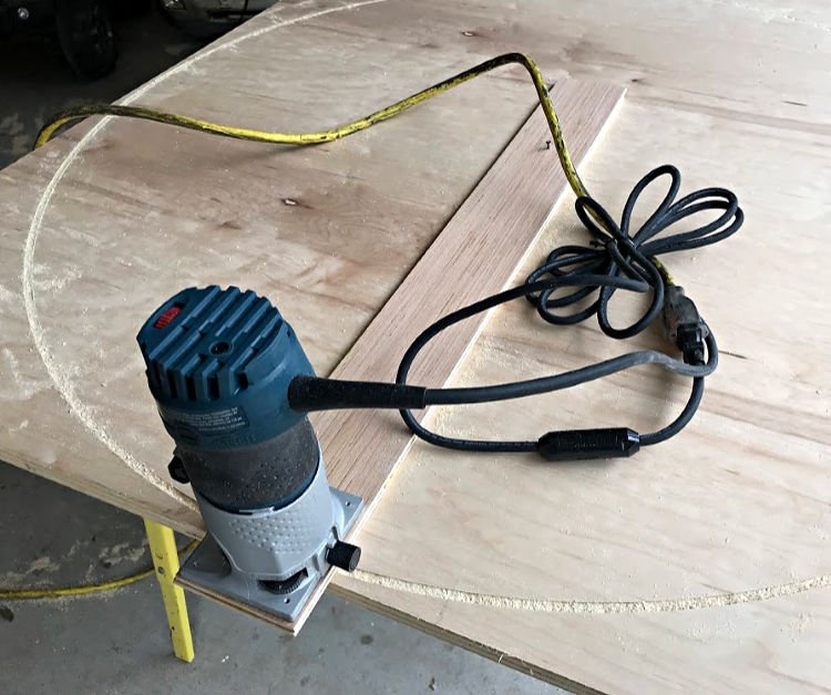 Circle cutting jig attached to router to cut a DIY round plywood table top.