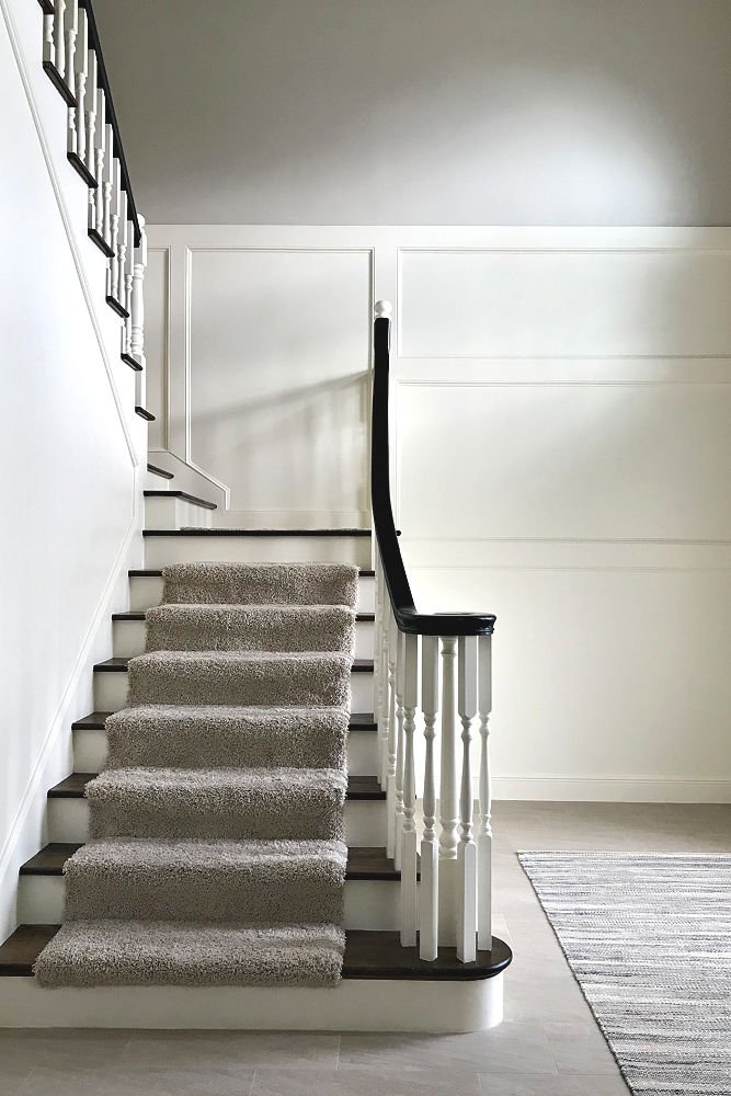 A white foyer with traditional stairs and with wood trim finish carpentry.